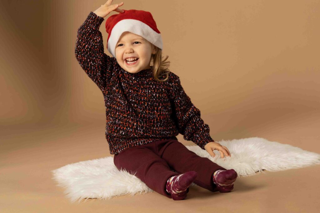 Familienbilder zu Weihnachten. Kind mit Weihnachtsmütze lacht